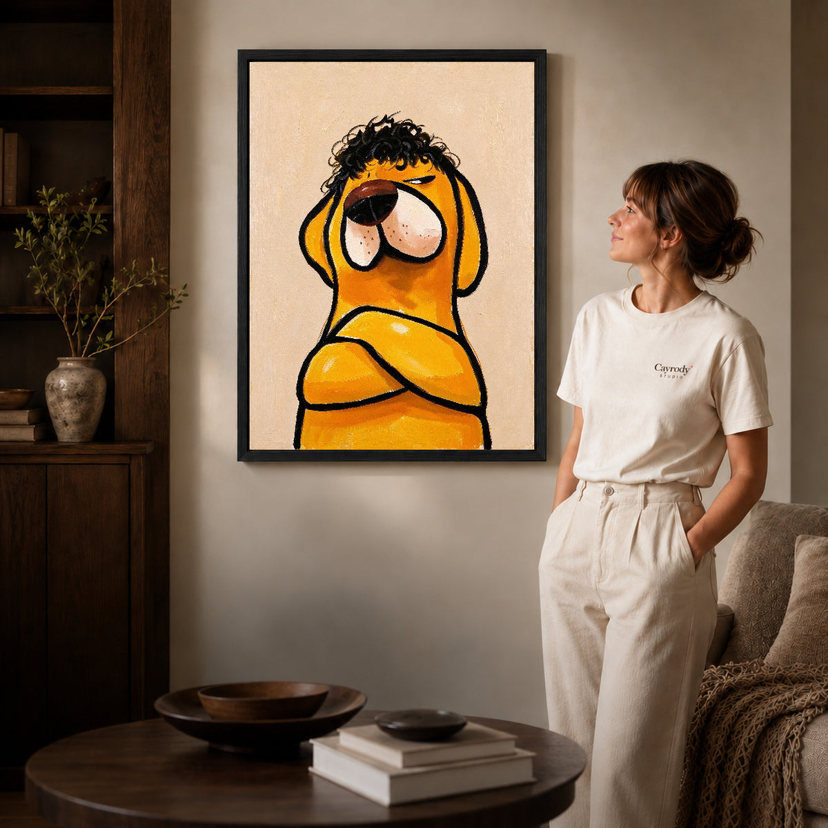 curly haired dog canvas art in a black frame beside a woman and round wooden table.
