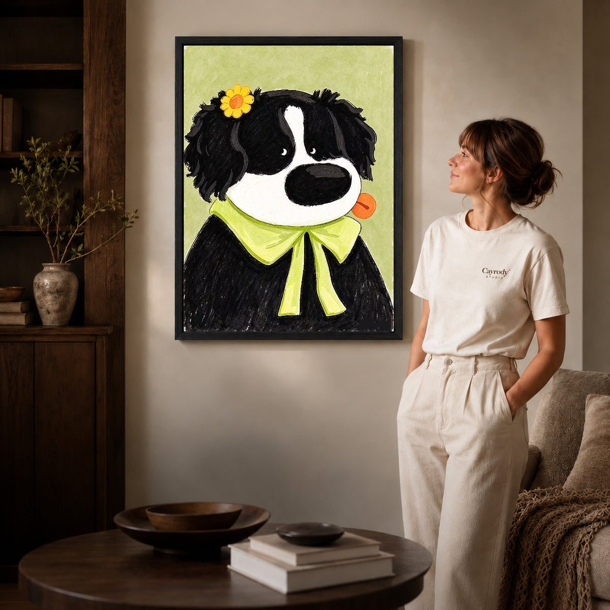 flower bow dog canvas art in a black frame beside a woman and round wooden table.
