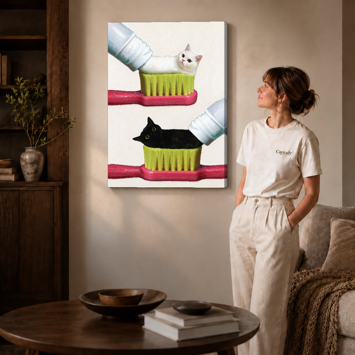 toothpaste kitten duo canvas art on gallery-wrapped canvas with natural edge shading beside a standing woman.