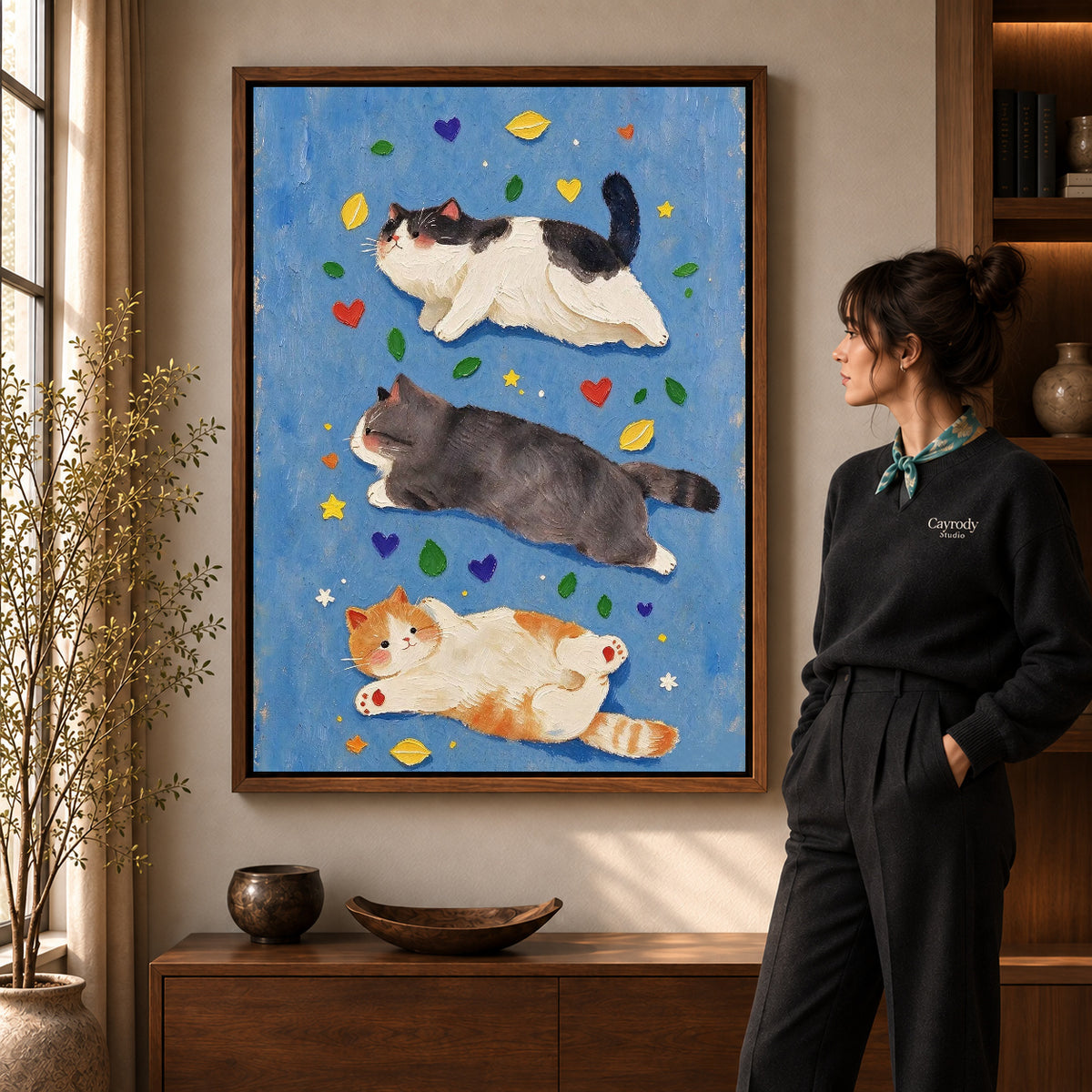 three resting cats canvas art shown in the walnut frame option within a warm living room.