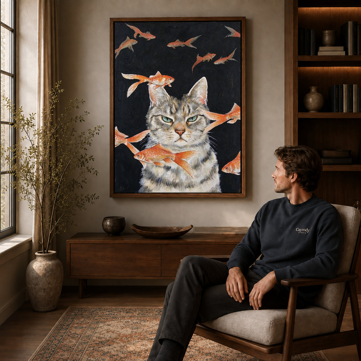 goldfish dreaming cat canvas art in a walnut frame above a console beside a seated man.