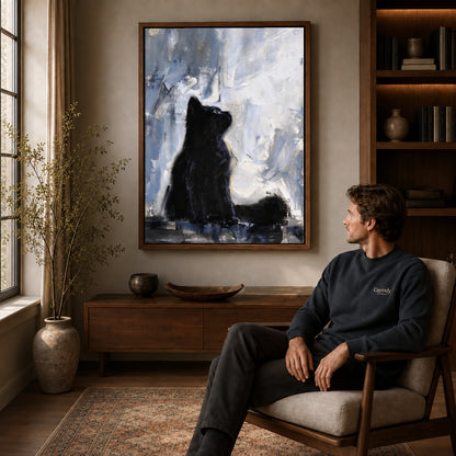 quiet black kitten canvas art in a walnut frame above a console beside a seated man.