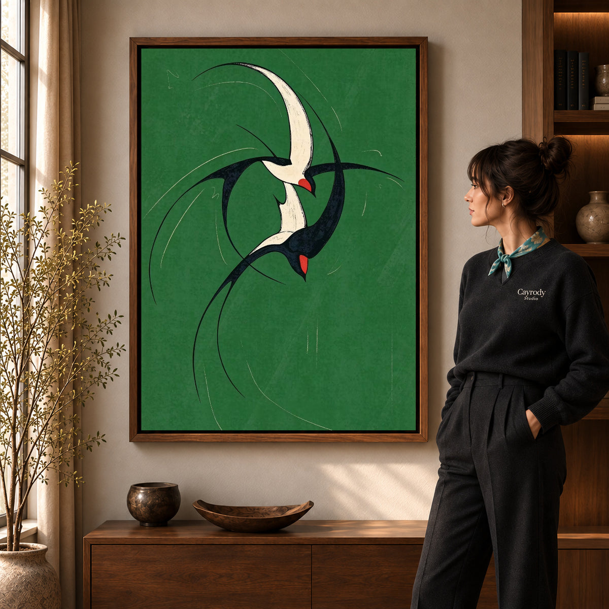 graceful swallow pair canvas art in a walnut frame beside a standing woman and wooden console.