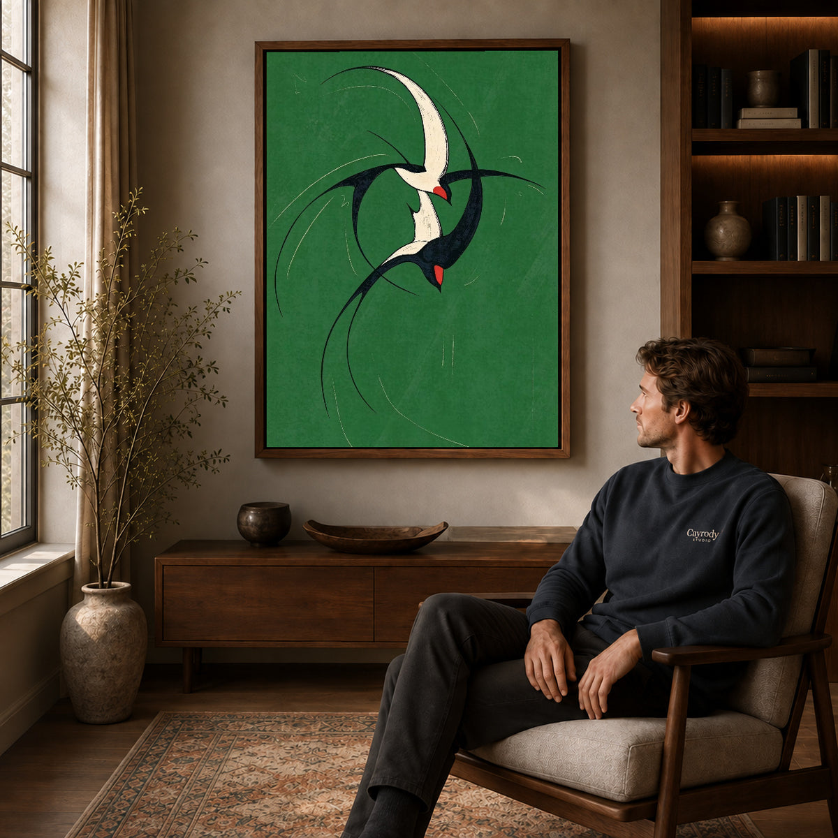 graceful swallow pair canvas art in a walnut frame above a console beside a seated man.