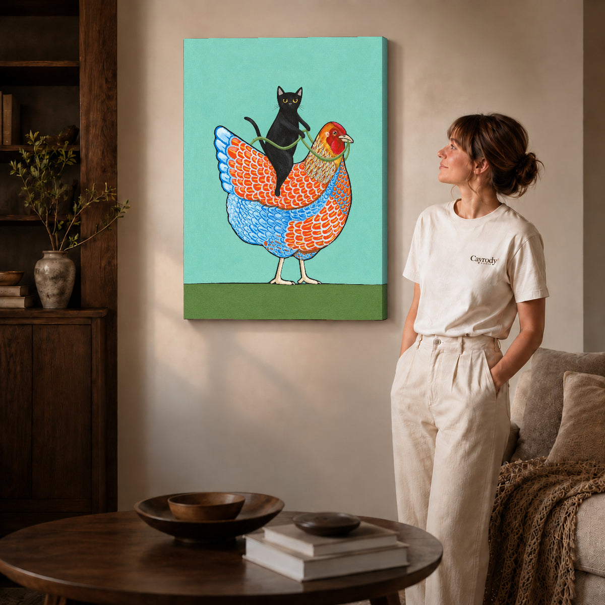 cat riding hen canvas art on gallery-wrapped canvas with natural edge shading beside a standing woman.