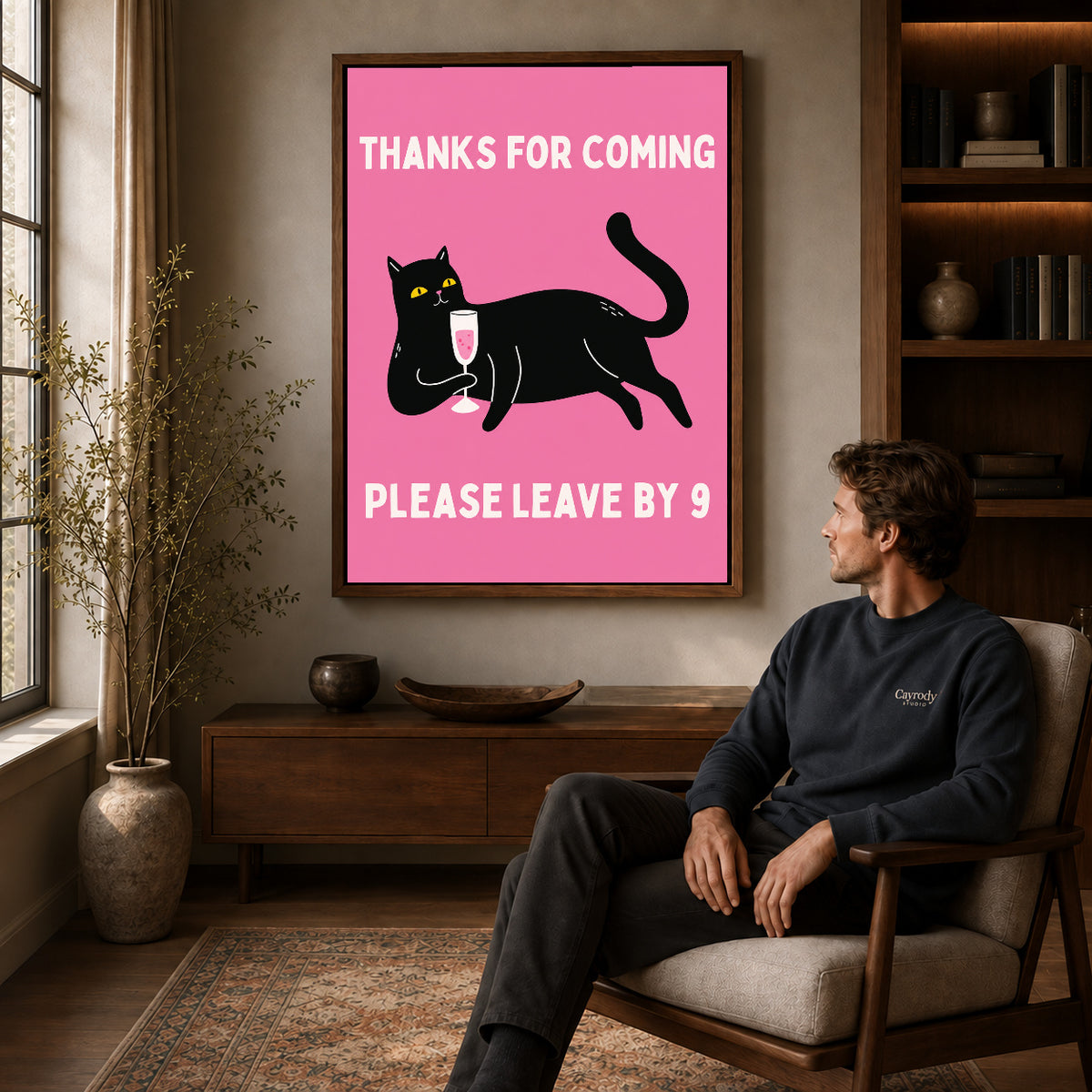 early goodbye cat canvas art in a walnut frame above a console beside a seated man.