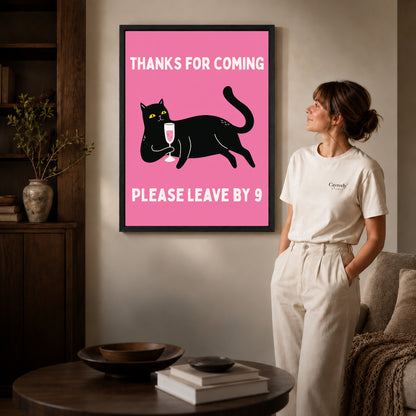 early goodbye cat canvas art in a black frame beside a woman and round wooden table.