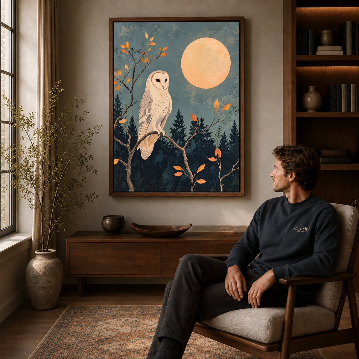 moonlit barn owl canvas art in a walnut frame above a console beside a seated man.