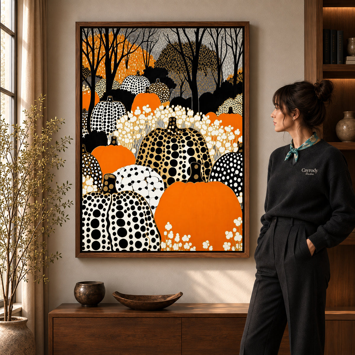 patterned pumpkin woods canvas art in a walnut frame beside a standing woman and wooden console.