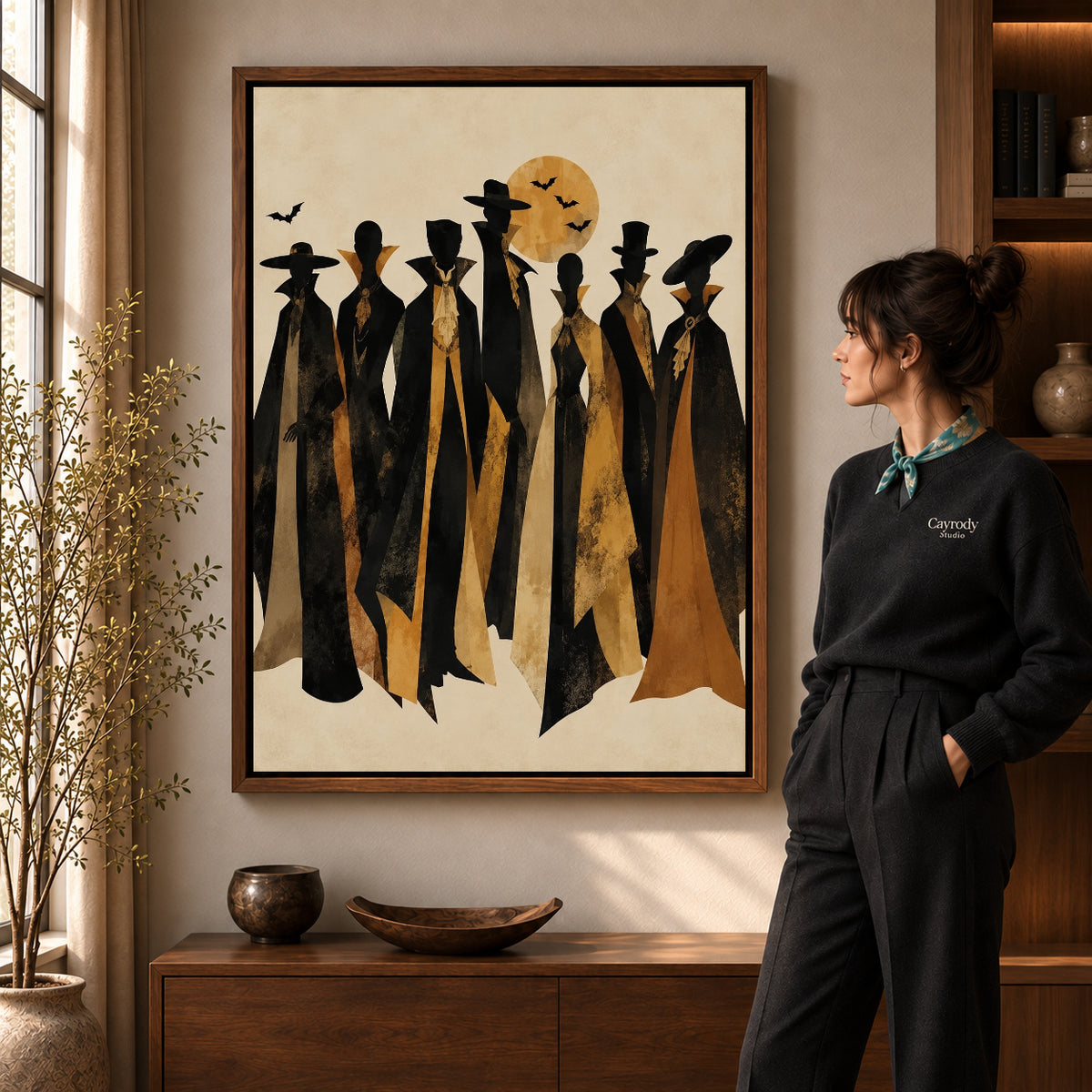 autumn cloaked gathering canvas art in a walnut frame beside a standing woman and wooden console.