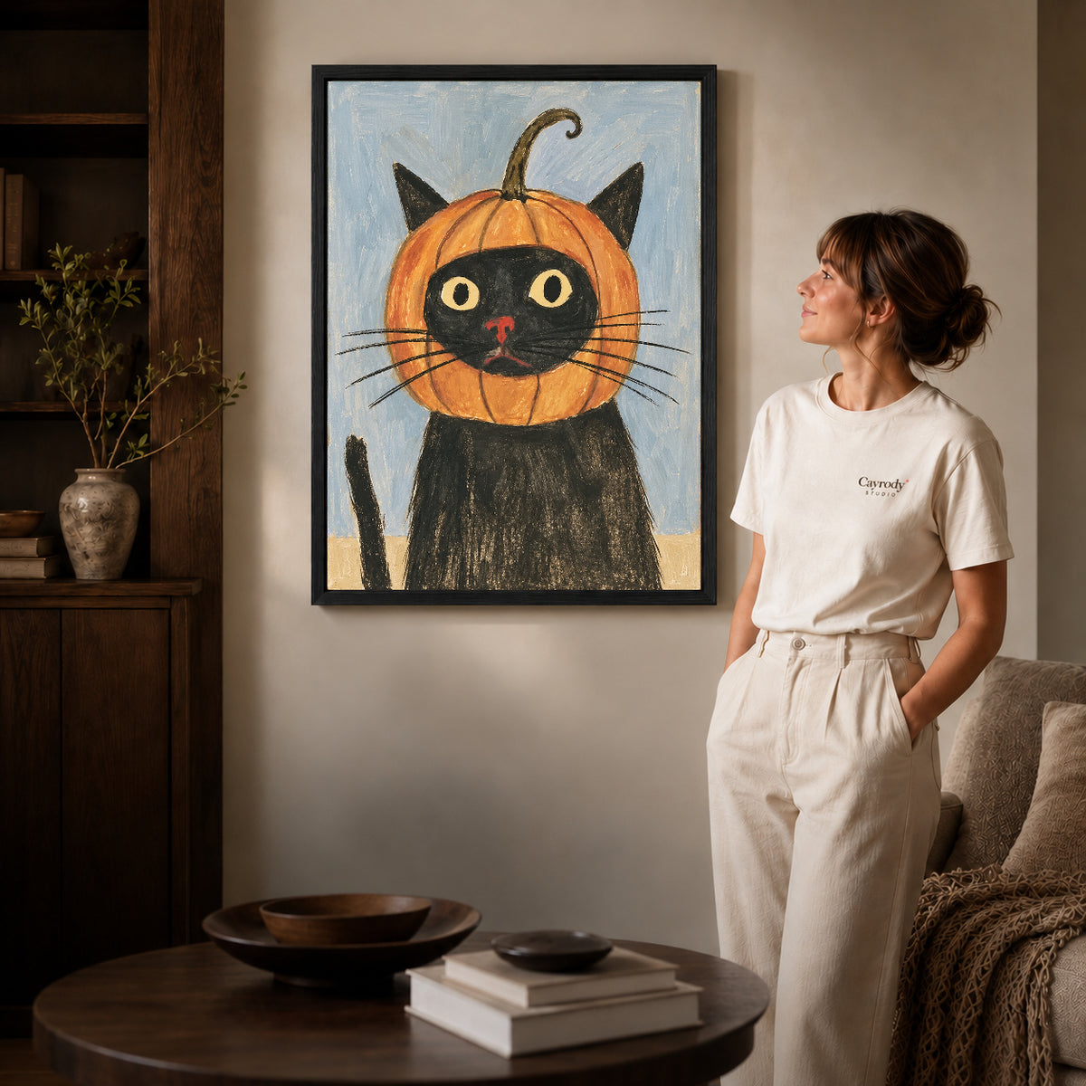 pumpkin hood cat canvas art shown in the black frame option against a softly lit wall.
