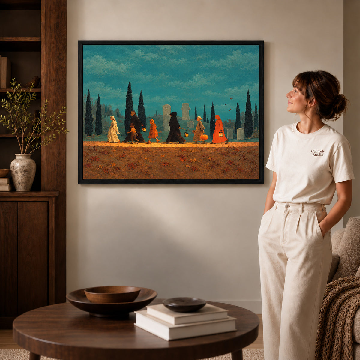 autumn lantern procession canvas art in a black frame beside a woman and round wooden table.