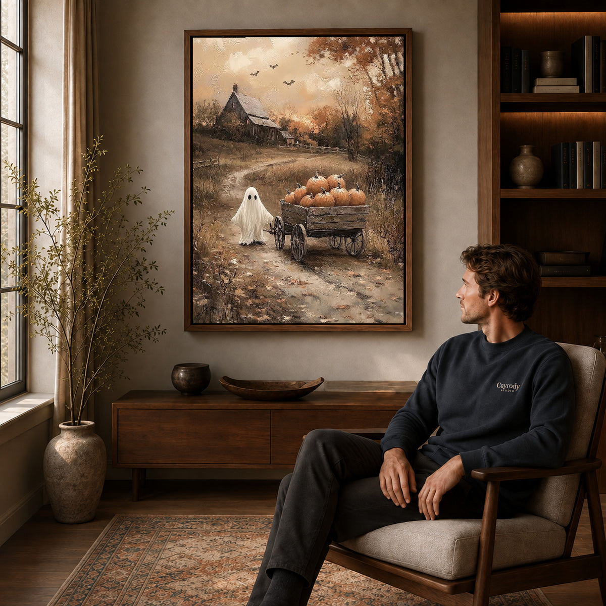 harvest wagon ghost canvas art in a walnut frame above a console beside a seated man.
