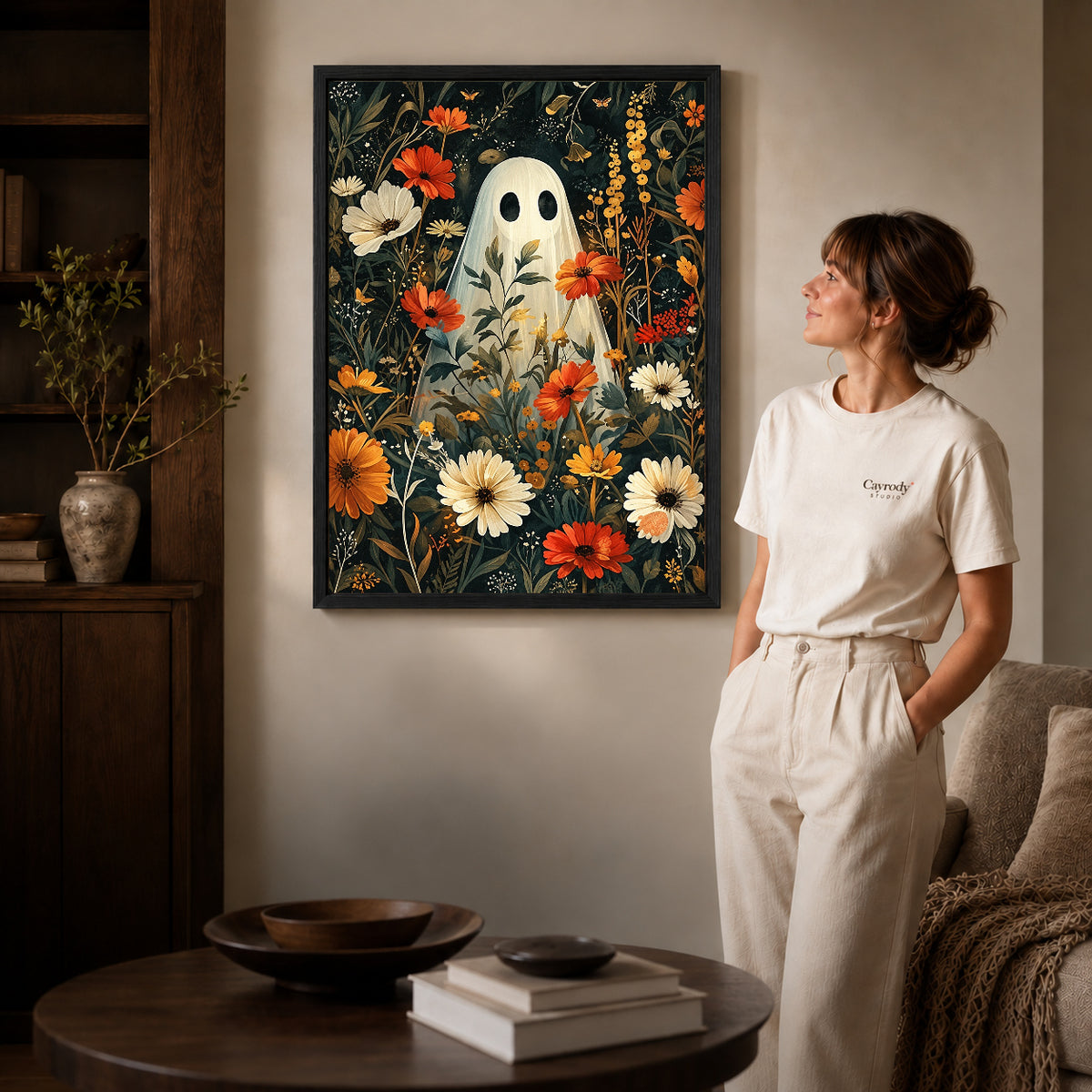 botanical ghost garden canvas art in a black frame beside a woman and round wooden table.