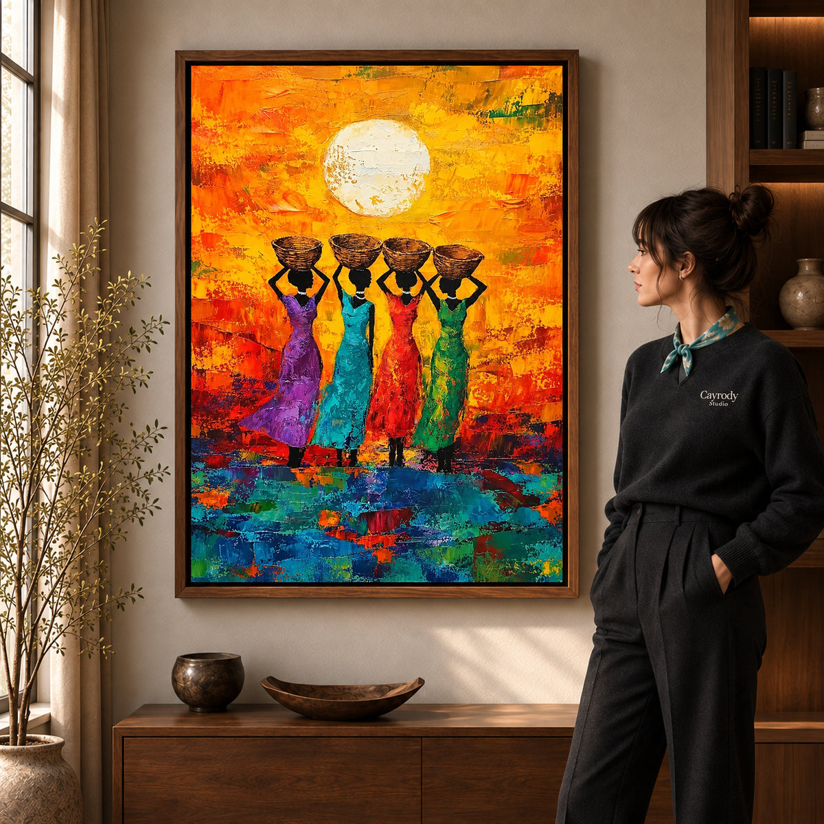 sunlit basket women canvas art in a walnut frame beside a standing woman and wooden console.