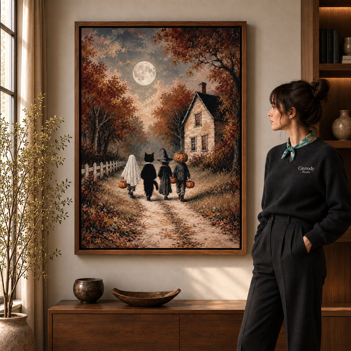 moonlit costume walk canvas art in a walnut frame beside a standing woman and wooden console.