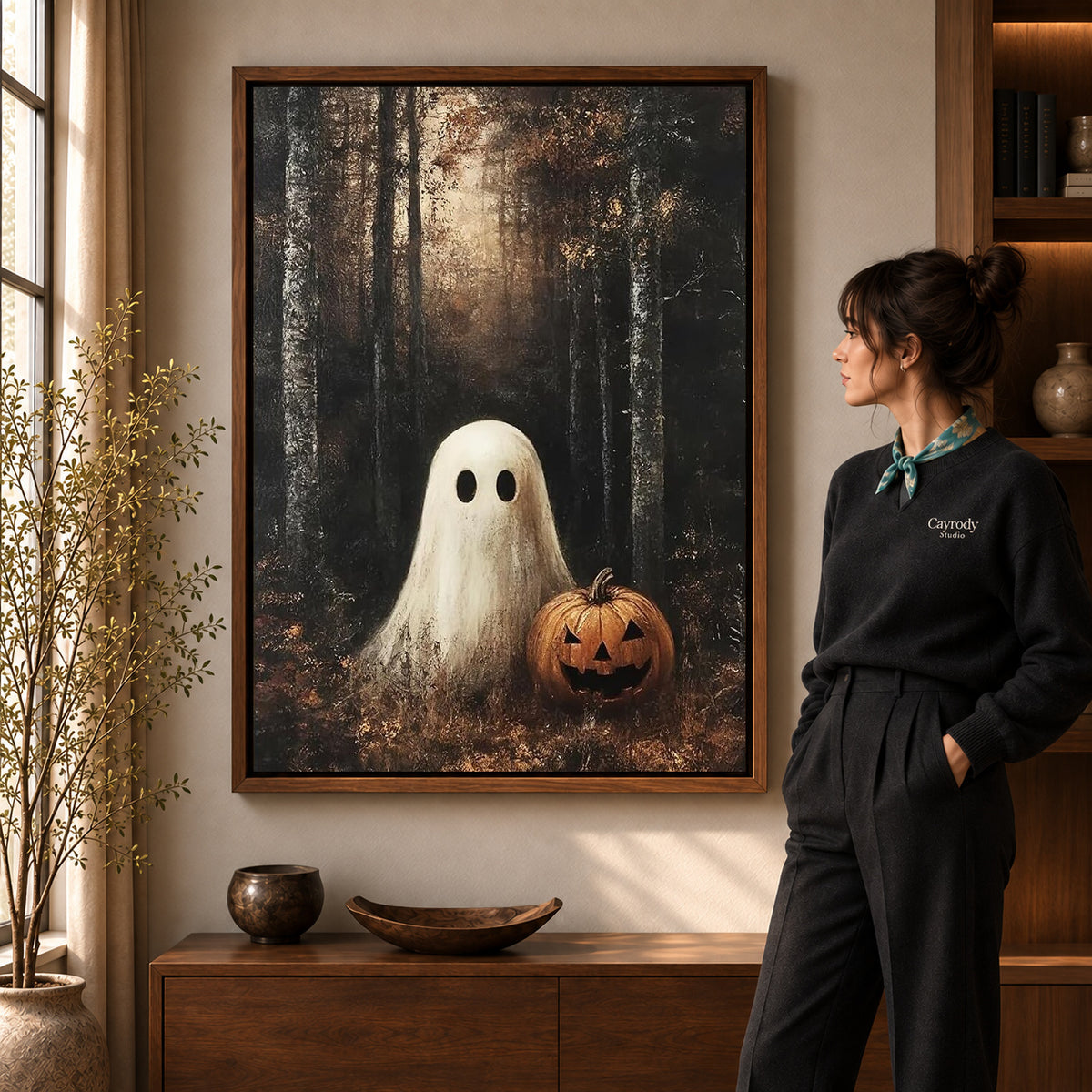 woodland pumpkin ghost canvas art in a walnut frame beside a standing woman and wooden console.