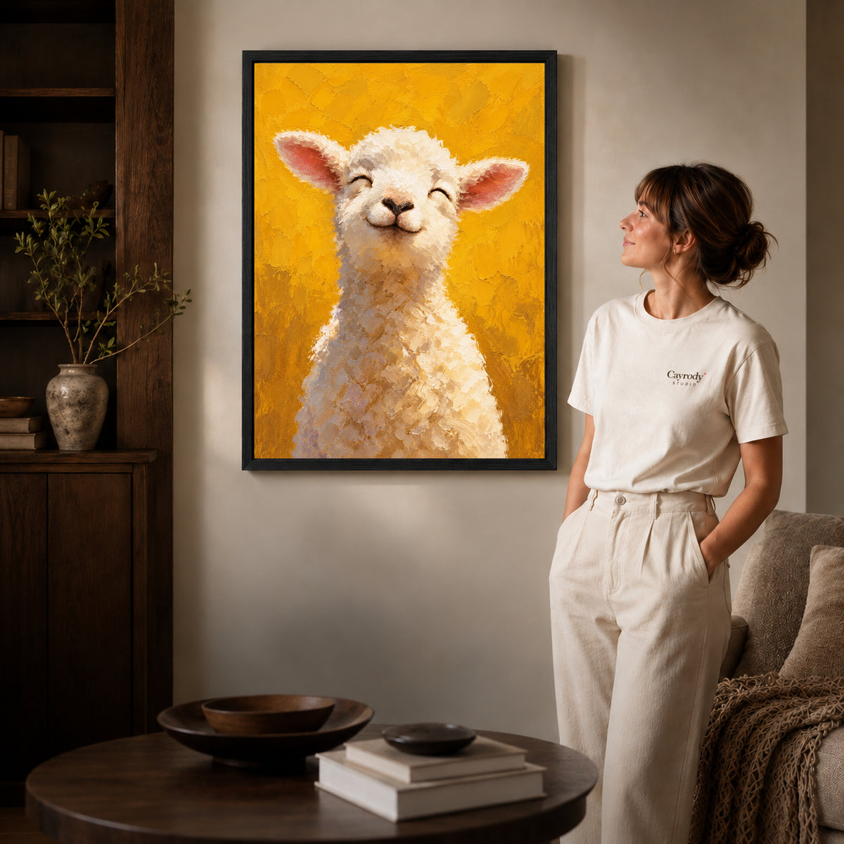 smiling golden lamb canvas art in a black frame beside a woman and round wooden table.