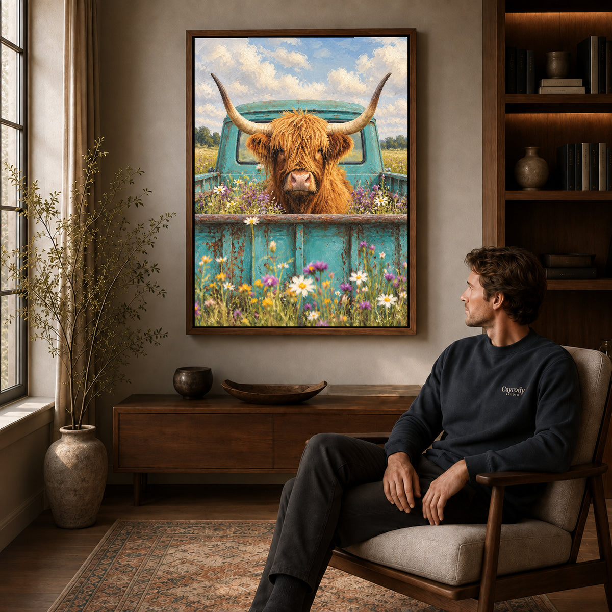highland cow pickup canvas art in a walnut frame above a console beside a seated man.