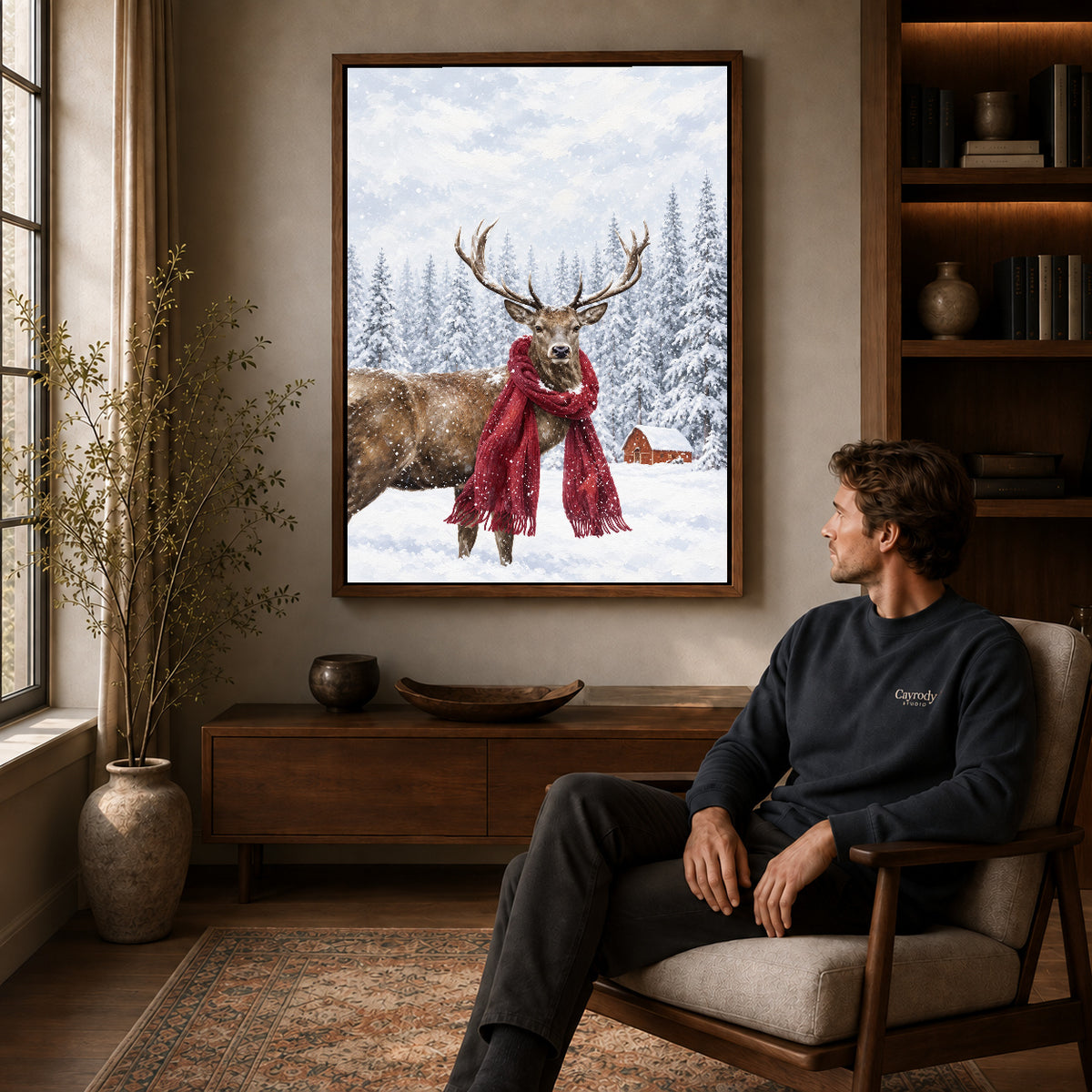 snowy scarf deer canvas art in a walnut frame above a console beside a seated man.