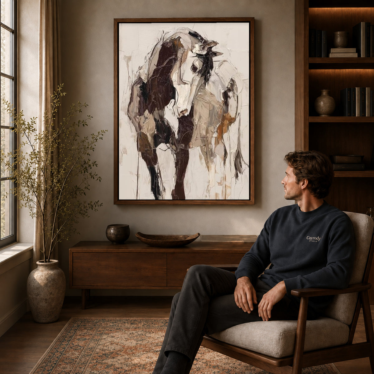 expressive abstract cow canvas art in a walnut frame above a console beside a seated man.