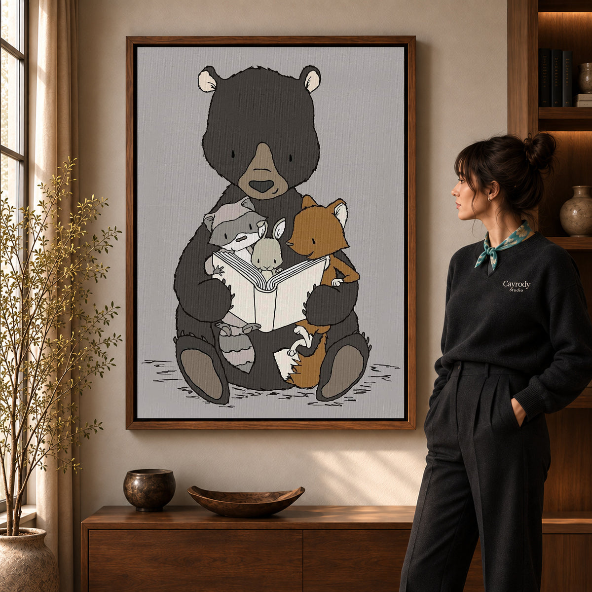 woodland storytime friends canvas art in a walnut frame beside a standing woman and wooden console.