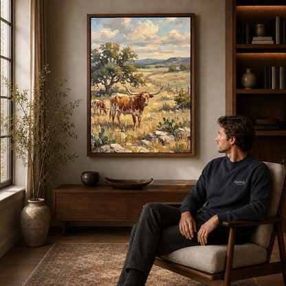 golden longhorn pasture canvas art in a walnut frame above a console beside a seated man.