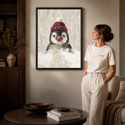 snowy penguin companion canvas art in a black frame beside a woman and round wooden table.