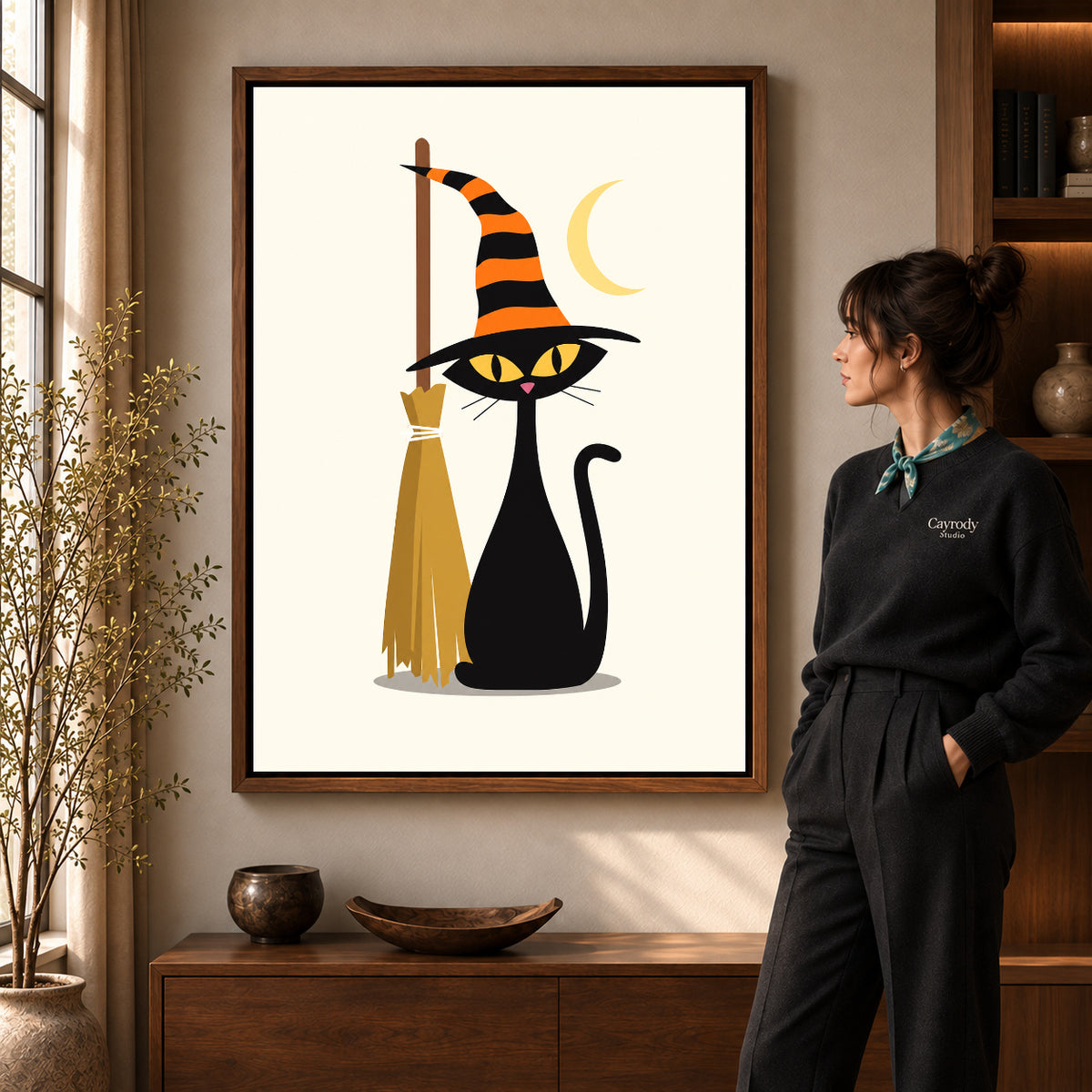 striped hat cat canvas art in a walnut frame beside a standing woman and wooden console.