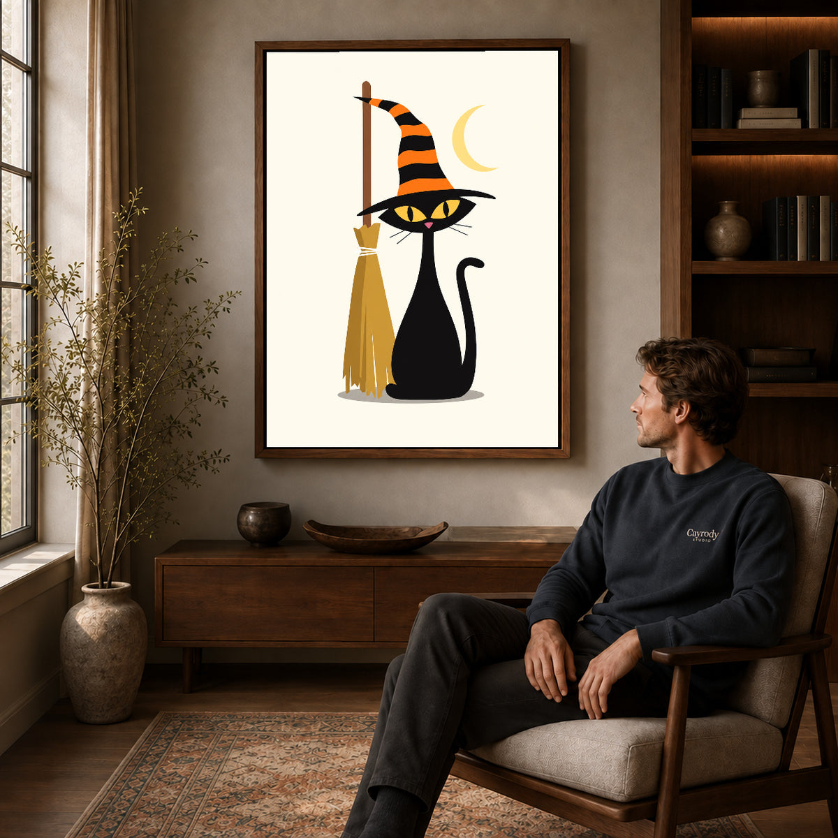 striped hat cat canvas art in a walnut frame above a console beside a seated man.
