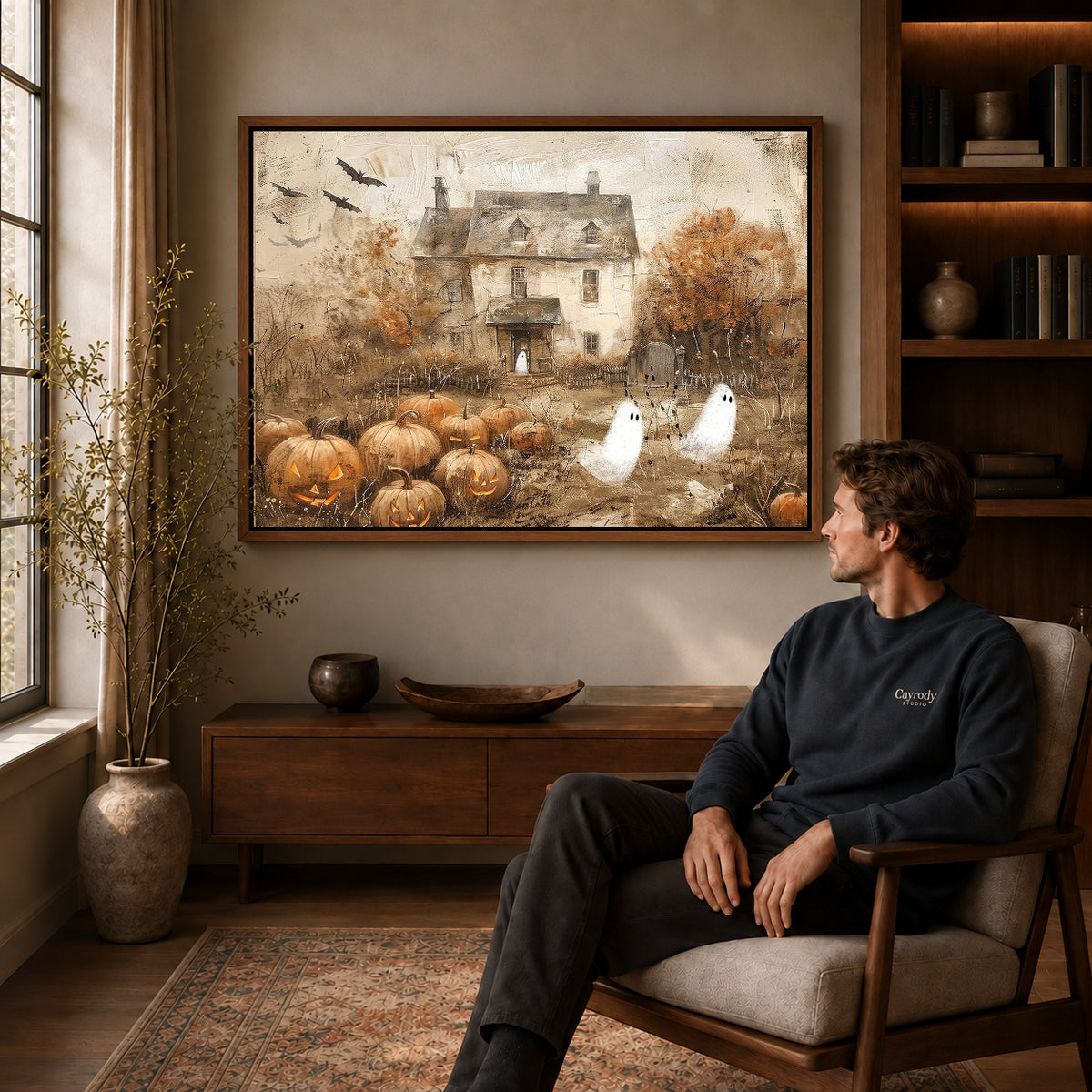 vintage ghost cottage canvas art in a walnut frame above a console beside a seated man.
