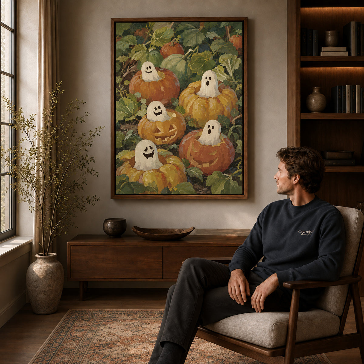 pumpkin ghost friends canvas art in a walnut frame above a console beside a seated man.