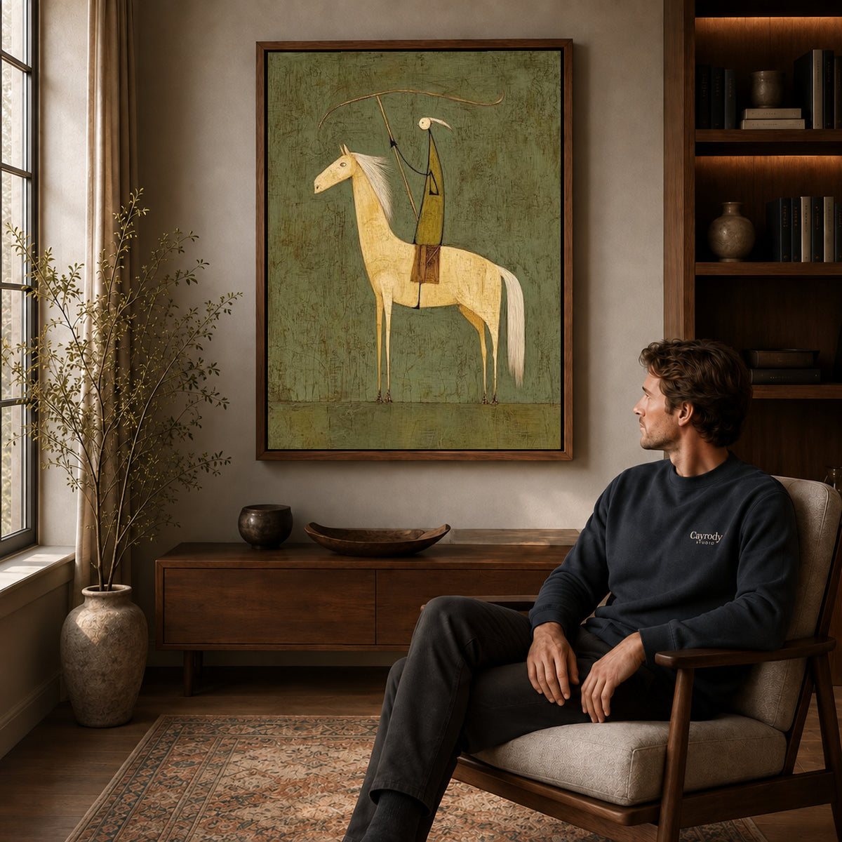 quiet lasso rider canvas art in a walnut frame above a console beside a seated man.
