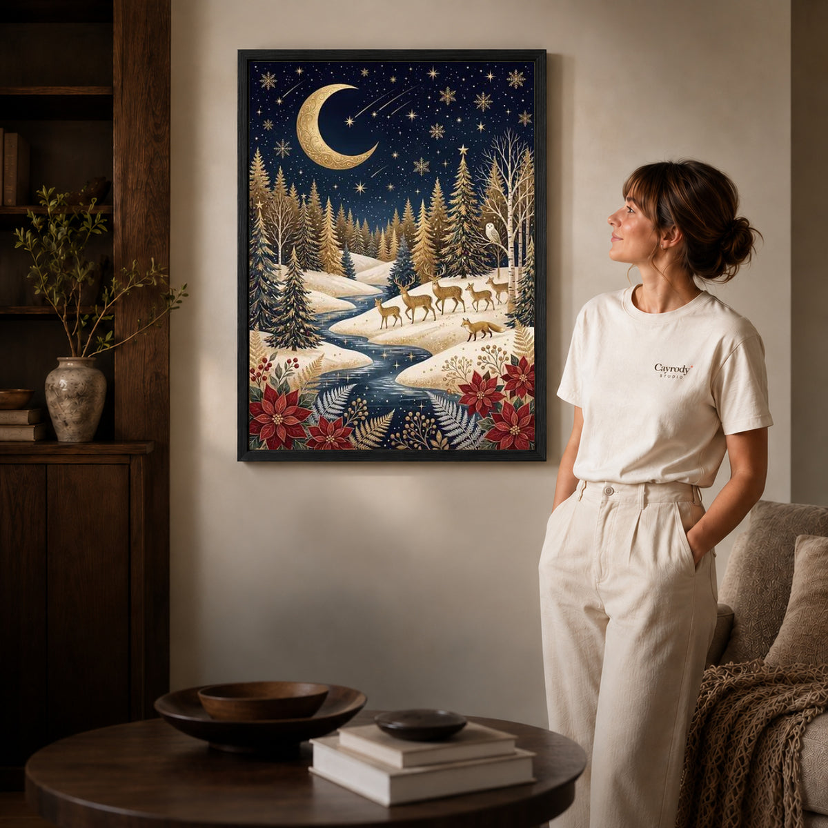 golden winter forest canvas art in a black frame beside a woman and round wooden table.