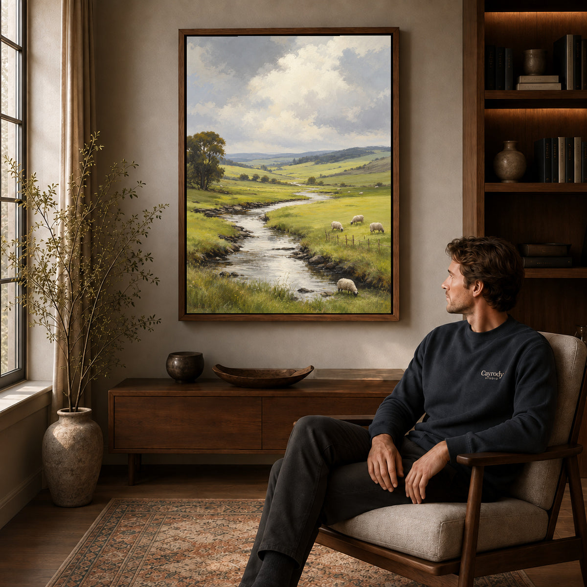 quiet sheep valley canvas art in a walnut frame above a console beside a seated man.