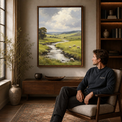 quiet sheep valley canvas art in a walnut frame above a console beside a seated man.