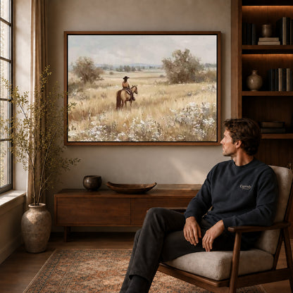 quiet prairie rider canvas art in a walnut frame above a console beside a seated man.