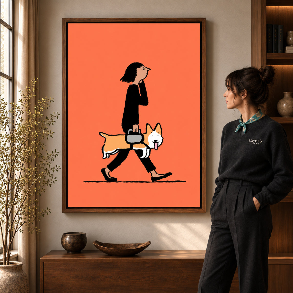 walking corgi companion canvas art in a walnut frame beside a standing woman and wooden console.