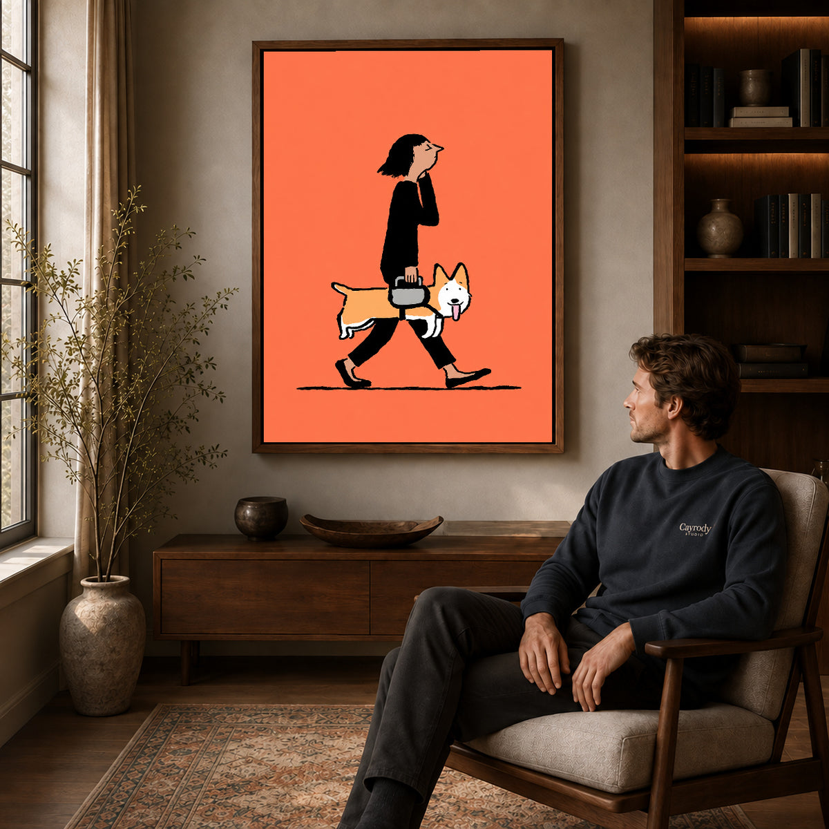 walking corgi companion canvas art in a walnut frame above a console beside a seated man.