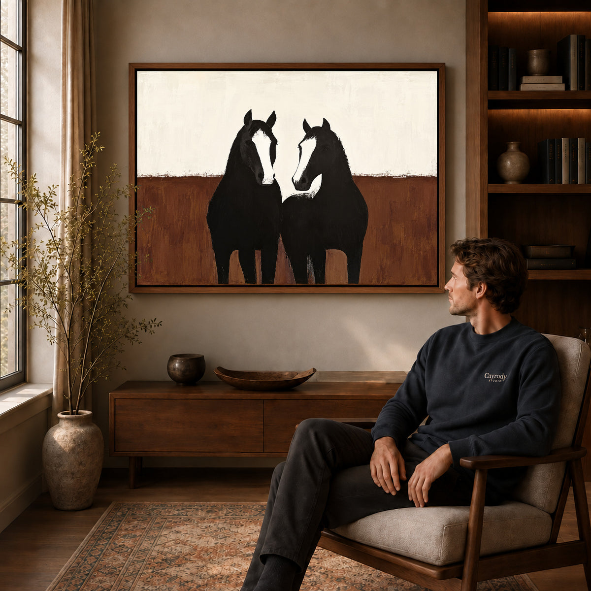 quiet horse companions canvas art in a walnut frame above a console beside a seated man.
