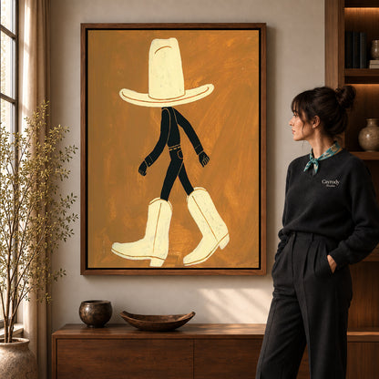 oversized cowboy boots canvas art in a walnut frame beside a standing woman and wooden console.