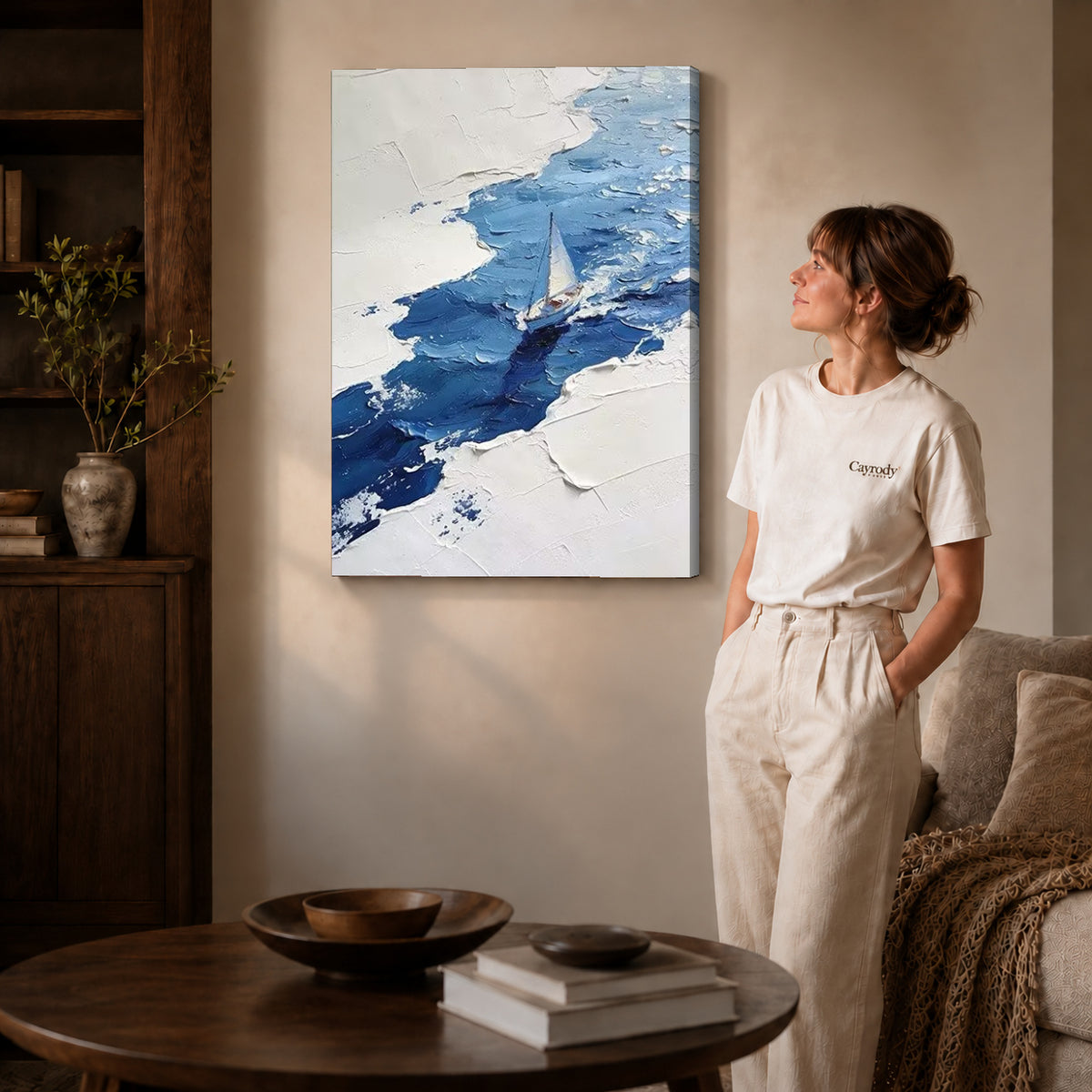 blue impasto sailboat canvas art on gallery-wrapped canvas with natural edge shading beside a standing woman.