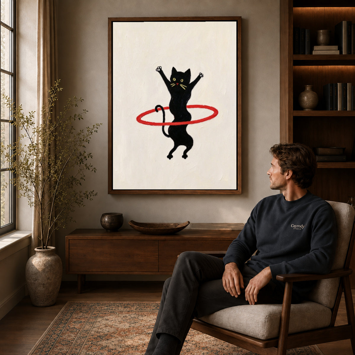 hula hoop cat canvas art in a walnut frame above a console beside a seated man.
