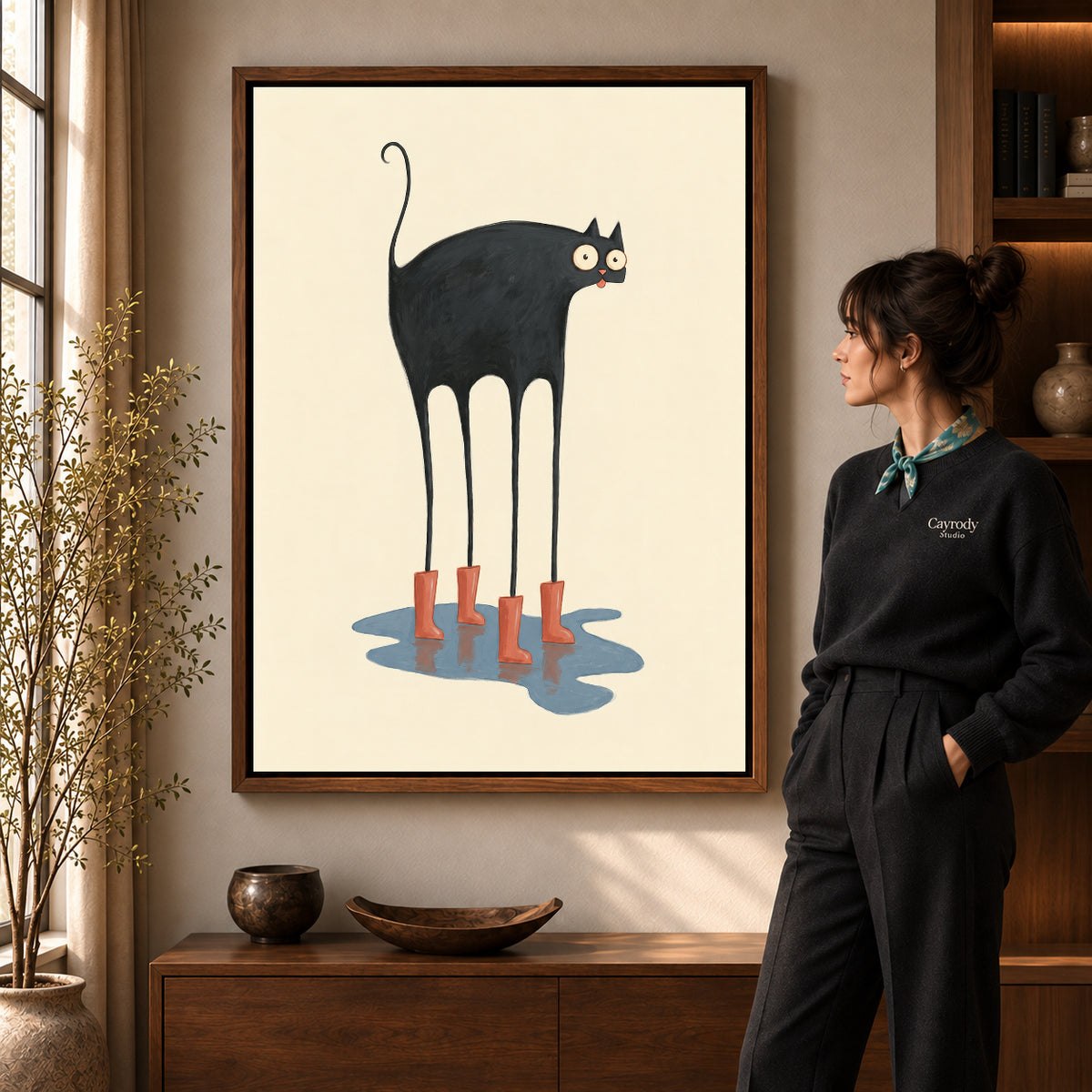 red boots cat canvas art in a walnut frame beside a standing woman and wooden console.