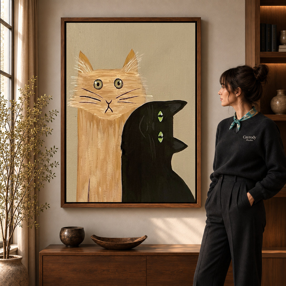 expressive cat gathering canvas art in a walnut frame beside a standing woman and wooden console.