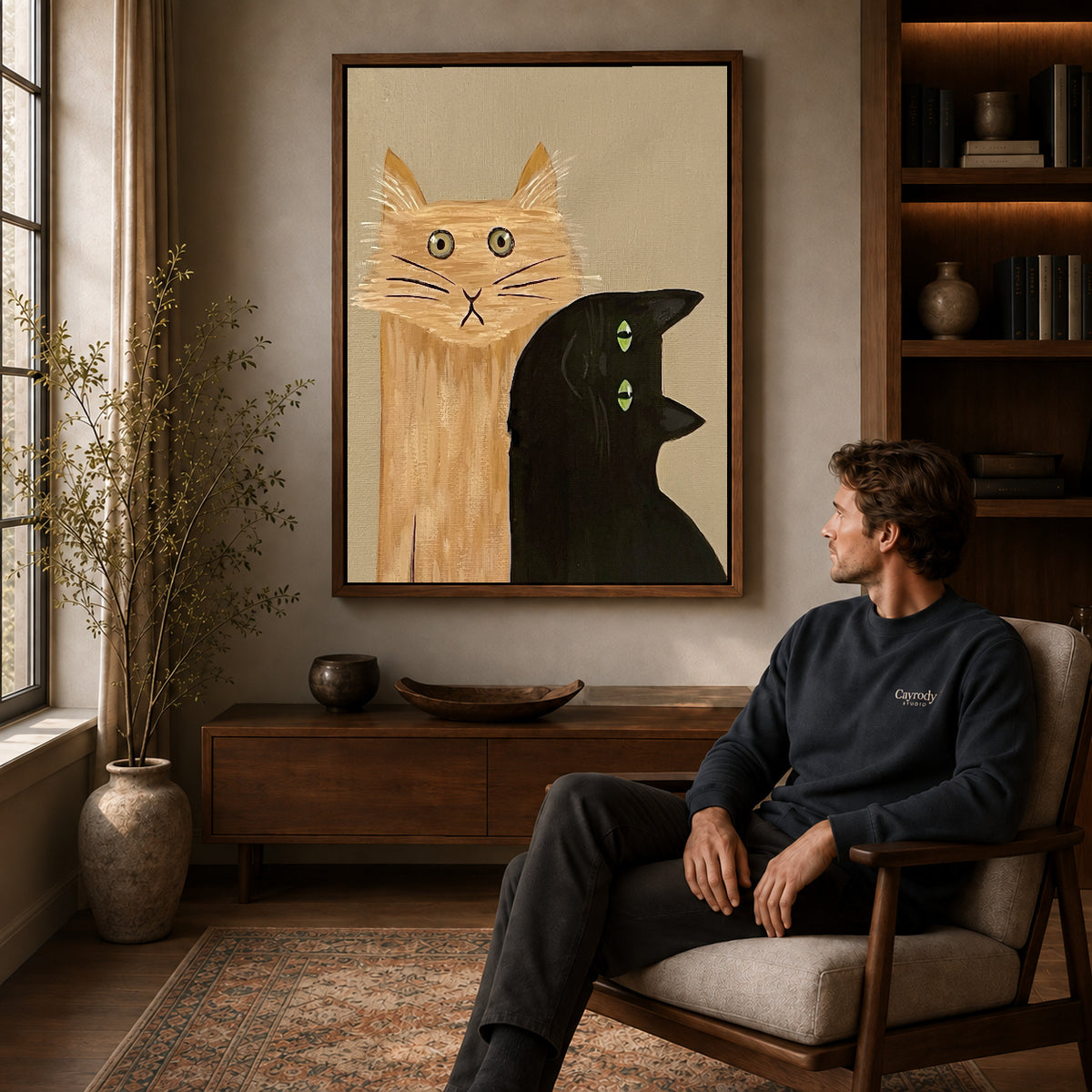 expressive cat gathering canvas art in a walnut frame above a console beside a seated man.