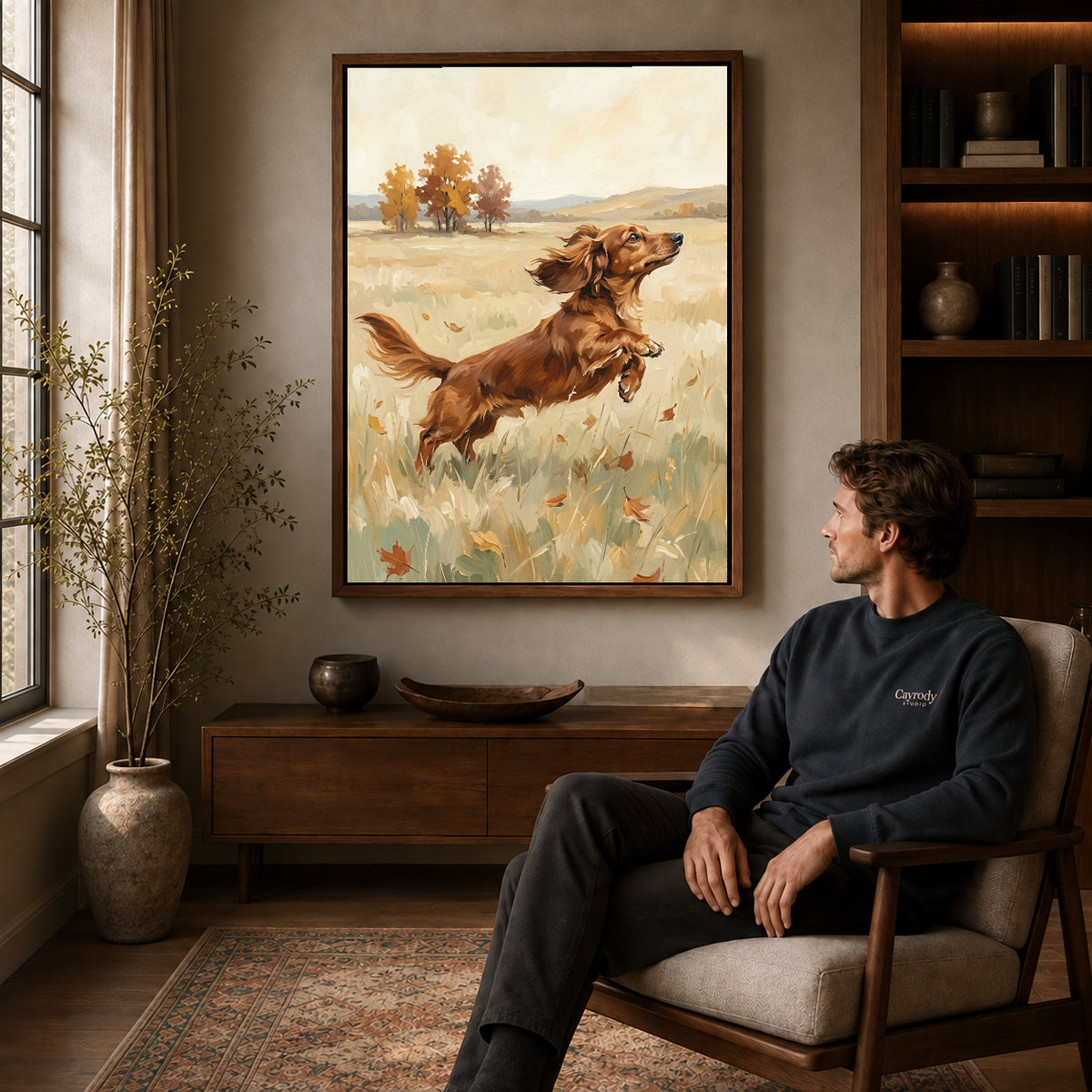 playful dachshund leap canvas art in a walnut frame above a console beside a seated man.
