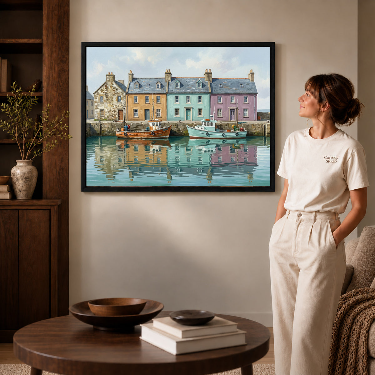 quiet harbor boats canvas art in a black frame beside a woman and round wooden table.