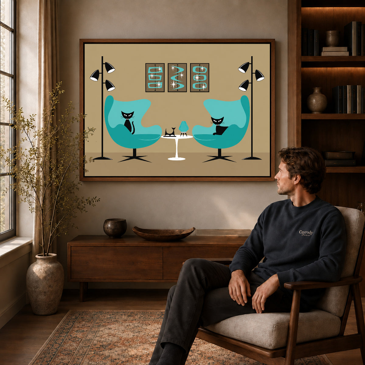 midcentury cat lounge canvas art in a walnut frame above a console beside a seated man.