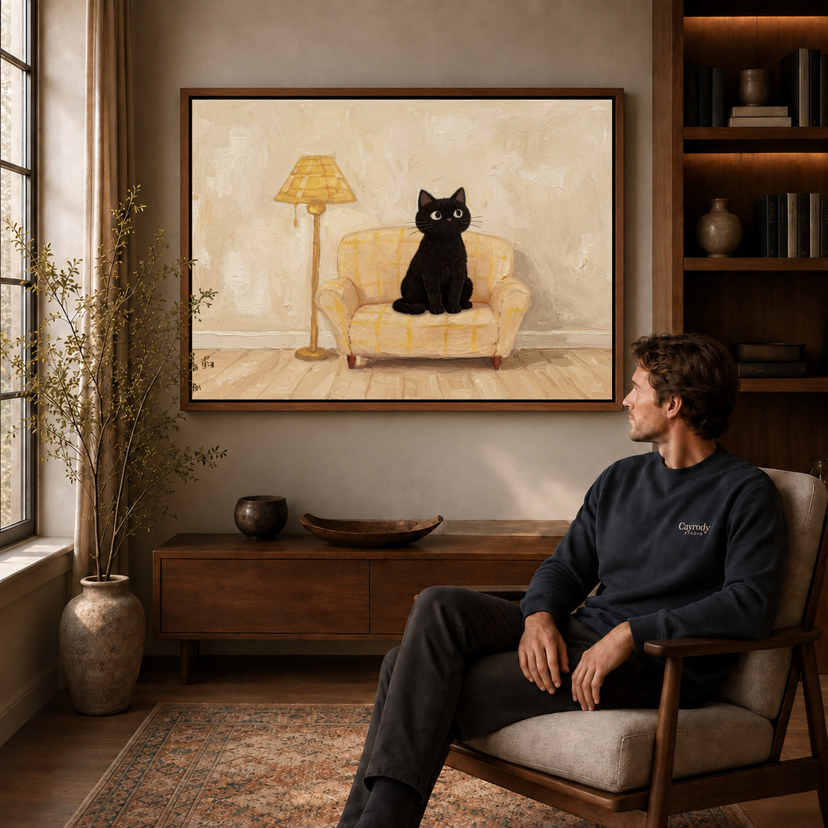 cozy armchair cat canvas art in a walnut frame above a console beside a seated man.